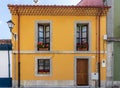 Traditional Spanish house. Old building restored, facade painted in yellow. Windows and balcony framed with grey stone. Wooden