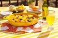 traditional spanish paella dish on vibrant yellow tablecloth