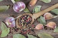 traditional spices for the kitchen. bay leaf, mixture of various peppers in a spoon and garlic on a wooden table. top view Royalty Free Stock Photo