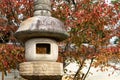 Traditional stone carved Japanese lantern Toro in Ninna-ji Temple Complex park in Kyoto, Japan with red autumn leaves. Royalty Free Stock Photo