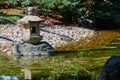 Traditional stone toro lantern on the edge of the pond at the Nagoya castle garden. Japan