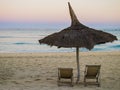 Traditional straw beach umbrella and two deckchairs facing the peaceful Indian Ocean coast, Anakao, Madagascar