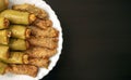 Traditional stuffed squash and cabbage rolls on white plate on dark wooden background with copy space.