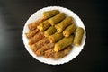 Traditional stuffed squash and cabbage rolls on white plate on dark wooden background