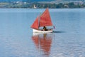 Traditional style red sails on small yacht becalmed in bay Royalty Free Stock Photo