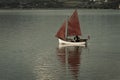 Traditional style red sails on small yacht becalmed in bay Royalty Free Stock Photo