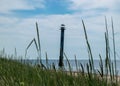 Traditional summer landscape with sandy and pebbly promontory, green dune grass, abandoned sloping Kiipsaare lighthouse in