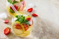 Traditional summer Mojito drink with lemon and strawberry with copy space on brown stone background.