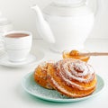 Traditional Swedish fika or cinnamon bun on white breakfast table.