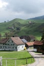 Traditional Swiss landscape with rural houses against the background of a green hill.