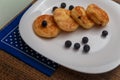 Traditional syrniki or cottage cheese pancakes with blueberries on white plate with blue napkin on kitchen table