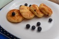 Traditional syrniki or cottage cheese pancakes with blueberries on white plate with blue napkin on kitchen table