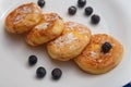 Traditional syrniki or cottage cheese pancakes with blueberries on white plate with blue napkin on kitchen table