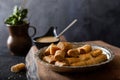 Traditional tahini crispy roll with bowl of tahini on wooden background. Dry Baklava with Tahini or Tahini Crispy