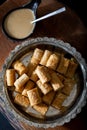Traditional tahini crispy roll with bowl of tahini on wooden background. Dry Baklava with Tahini or Tahini Crispy