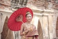 Traditional Thai dress. Beautiful women wearing a traditional Thai cloth as a wedding dress holding a red umbrella outdoor Royalty Free Stock Photo