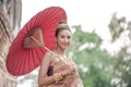 Traditional Thai dress. Beautiful women wearing a traditional Thai cloth as a wedding dress holding a red umbrella outdoor