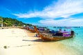 Traditional Thai fishing wooden boats wrapped with colored ribbons. At sand coast of tropical island