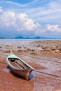 Traditional longtail boat on the sand beach at the low tide. Sea view with islands on horizon and clouds in the sky. Royalty Free Stock Photo