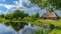 Traditional thatched roof house beside a pond with lily pads and green landscape Royalty Free Stock Photo