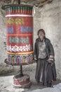 Traditional tibetan old woman turning an old prayer wheel in the village of Lamayuru, region of Leh, Ladakh, India.