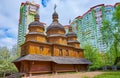 The old timber church against the modern residential high-rises, Mamajeva Sloboda Cossack Village, Kyiv, Ukraine