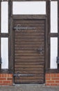 Traditional timber-framed wall with old wooden door and heavy iron hinges Royalty Free Stock Photo