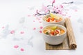 Traditional Tom Yum soup with blooming sakura branch on white stone table Royalty Free Stock Photo