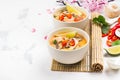 Traditional Tom Yum soup with blooming sakura branch on white stone table Royalty Free Stock Photo