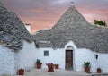 Traditional trulli houses on street in the Aia Piccola area of Alberobello. Photographed early morning with red sky. Royalty Free Stock Photo