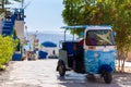 Traditional tuk-tuk moto taxi is waiting for passengers on empty road to sea at resort. Popular three-wheeler vehicle in Royalty Free Stock Photo