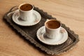 Traditional Turkish coffee in a patterned white cup in a metal tray on an oak coffee table Royalty Free Stock Photo