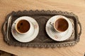 Traditional Turkish coffee in a patterned white cup in a metal tray on an oak coffee table Royalty Free Stock Photo