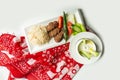 traditional turkish cuisine Izgara Kofte wuth rice, raita and salad in a dish isolated on colorful table cloth top view on grey