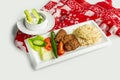 traditional turkish cuisine Izgara Kofte wuth rice, raita and salad in a dish isolated on colorful table cloth top view on grey