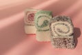 Traditional Turkish delight, rols shape, in coconut flakes , on pink background, sunlight, horizontal, no people,