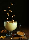 Traditional turkish drink boza with cinnamon and flying roasted chickpeas falling into a glass cup. Delicious winter beverage on