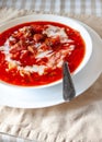 Traditional Ukrainian-Russian tomato borscht soup with sour cream in a white plate on the table. View from above Royalty Free Stock Photo