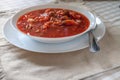 Traditional Ukrainian-Russian tomato borscht soup with sour cream in a white plate on the table. View from above. Royalty Free Stock Photo