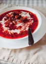 Traditional Ukrainian-Russian tomato borscht soup with sour cream in a white plate on the table. View from above Royalty Free Stock Photo