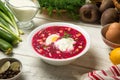 Traditional Ukrainian summer cold borscht with ingredients on a white wooden rustic table.