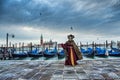 Venetian masked model from the Venice Carnival 2015 with Gondolas in the background near Plaza San Marco, Venezia, Italy Royalty Free Stock Photo