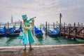 Venetian masked model from the Venice Carnival 2015 with Gondolas in the background near Plaza San Marco, Venezia, Italy