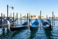Traditional Venetian gondolas tied to a wooden dock with poles in a canal in Venice, Italy. Royalty Free Stock Photo