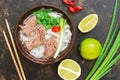 Traditional Vietnamese pho soup on a dark rustic background, lime, green onions, chili. View from above. Royalty Free Stock Photo