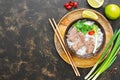 Traditional Vietnamese pho soup with rice noodles and beef in a bowl on a wooden tray. Dark background, top view, copy space. Royalty Free Stock Photo