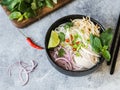 Traditional Vietnamese soup- pho ga in black bowl with chicken and rice noodles, mint and cilantro, green and red onion, chili, Royalty Free Stock Photo