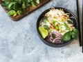 Traditional Vietnamese soup- pho ga in black bowl with chicken and rice noodles, mint and cilantro, green and red onion, chili, Royalty Free Stock Photo