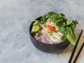 Traditional Vietnamese soup- pho ga in black bowl with chicken and rice noodles, mint and cilantro, green and red onion, chili, Royalty Free Stock Photo
