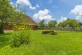 Traditional village house with blue sky, green grass, fence and trees. Ukraine. Royalty Free Stock Photo